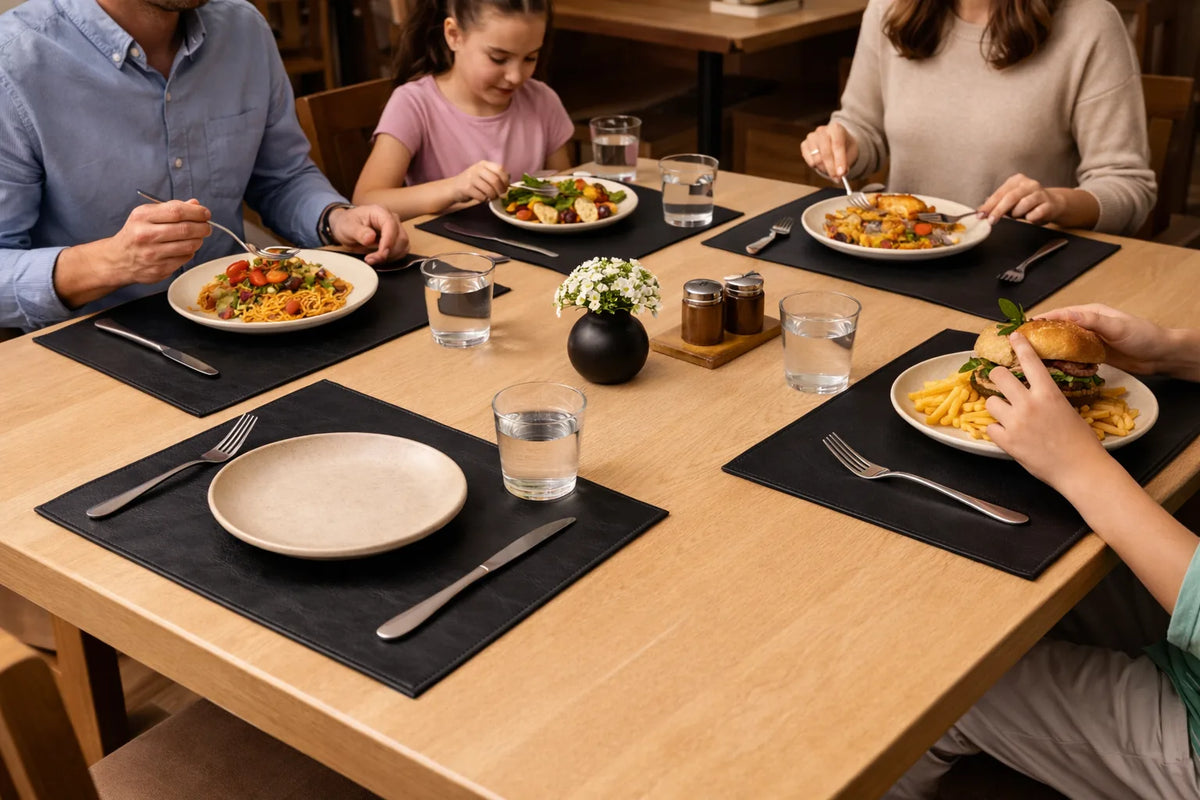 Black leather placemats with plates, cutlery and water glasses during a family meal.