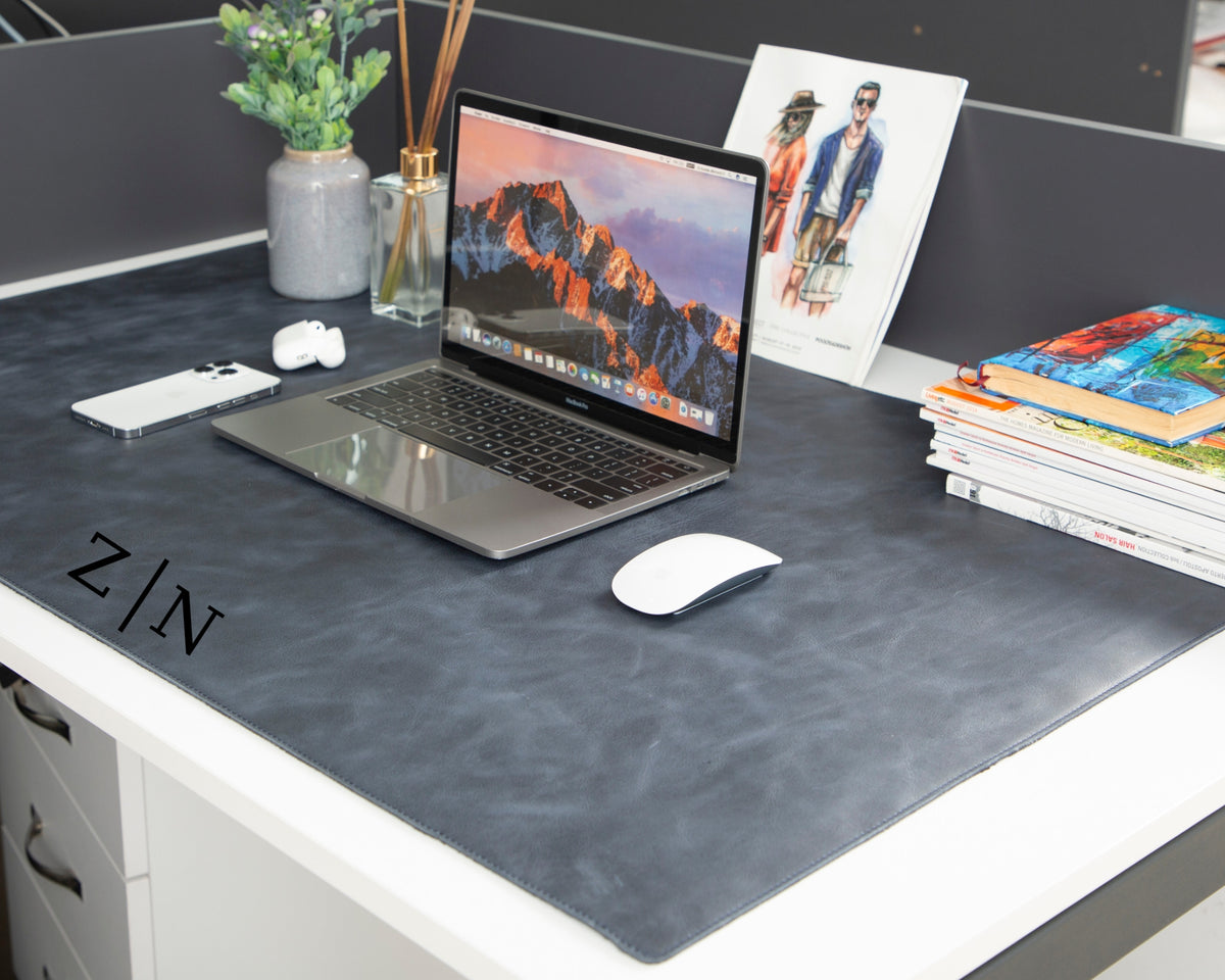 Navy blue full-grain leather desk mat in a workspace