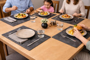 Gray leather placemats with cream plates and folded napkins during a family meal.