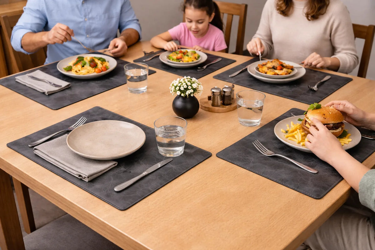 Gray leather placemats with cream plates and folded napkins during a family meal.