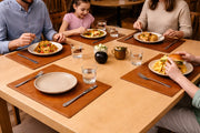 Warm brown leather placemats on a light wood table during a family meal.